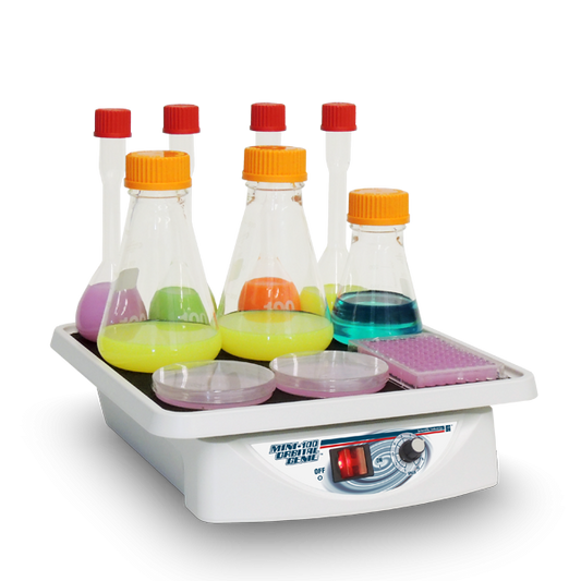 Laboratory hot plate with beakers containing colorful liquids on a white background