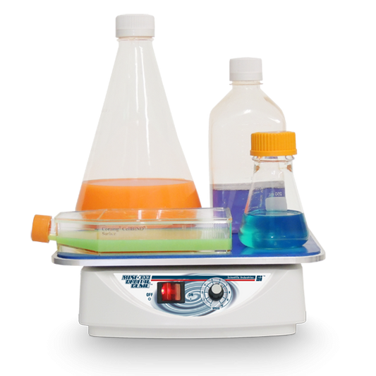 Laboratory hot plate with beakers containing colored liquids on a white background