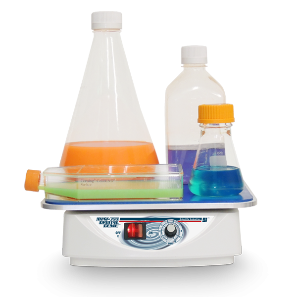 Laboratory hot plate with beakers containing colored liquids on a white background